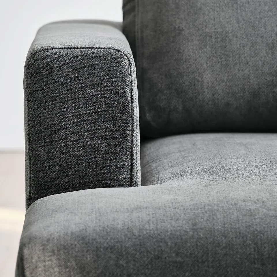 Modern sofa close-up, plush grey fabric, clean lines, sturdy armrest.