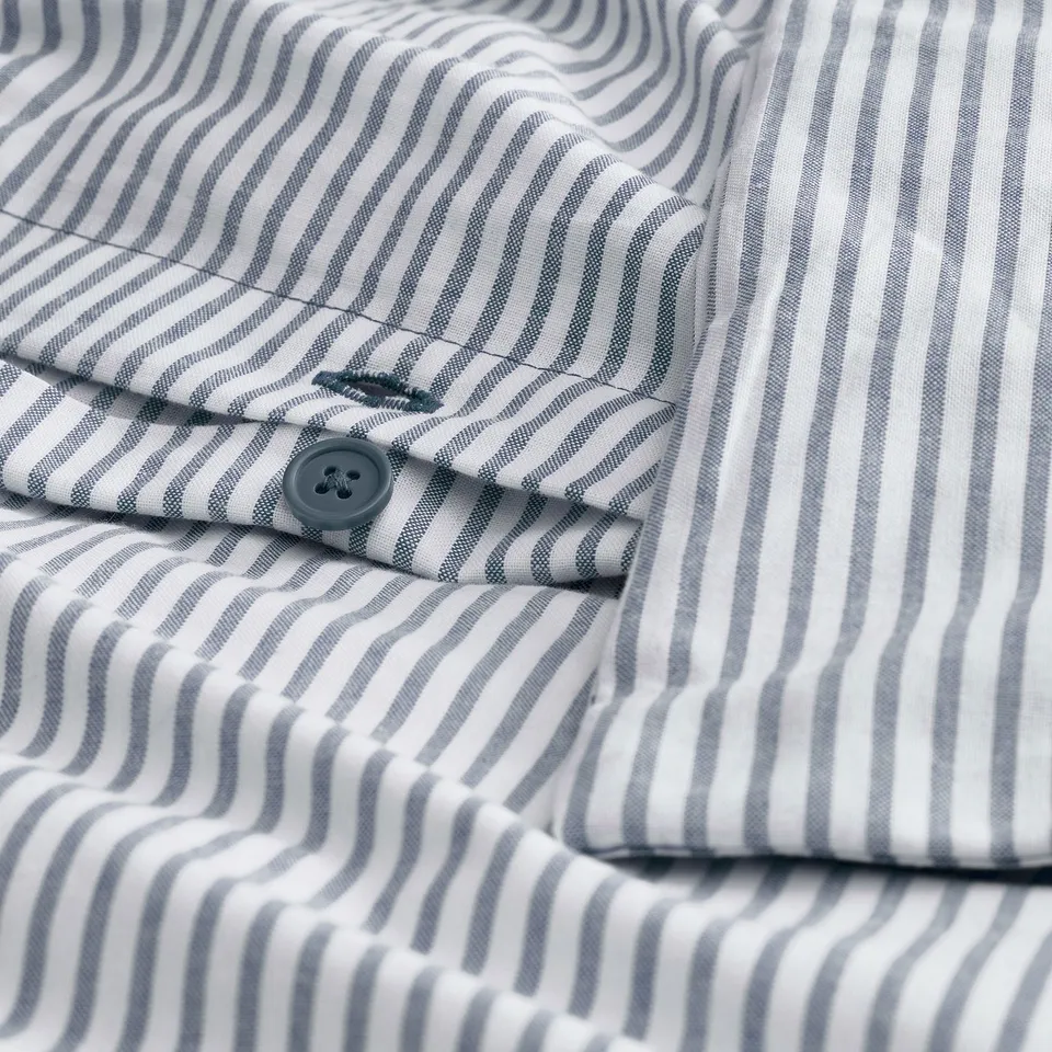 Close-up of a striped shirts cuff; shows button and stitching detail.
