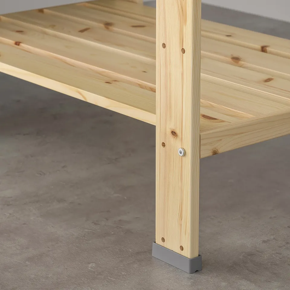 A wooden table leg protected by a grey HEJNE end cap to prevent damage from moisture and dirt.