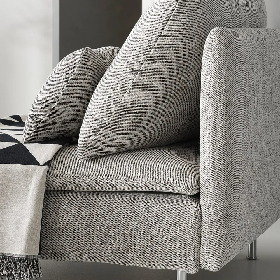 A modern, light grey SÖDERHAMN armchair. Its fabric is textured and it has a deep, comfortable seat with high legs and slim lines.