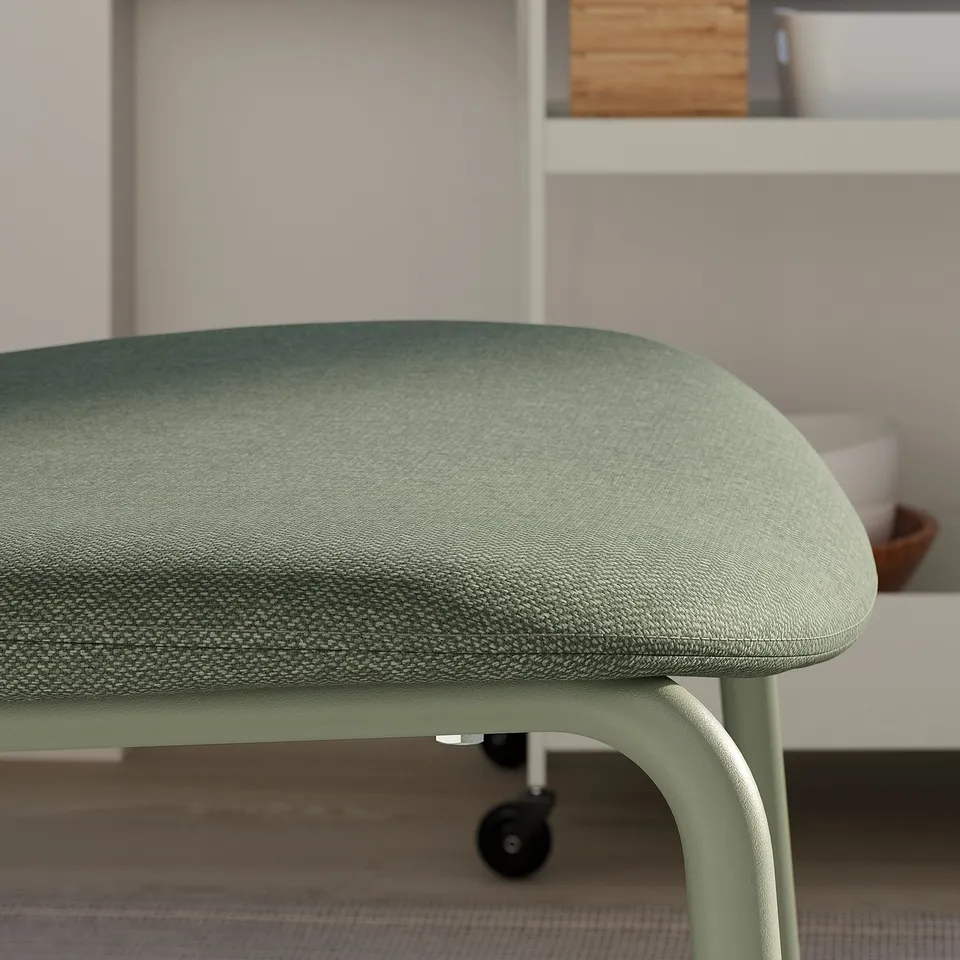 Green upholstered office chair on wheels near a desk, with a comfortable, well-cushioned seat.
