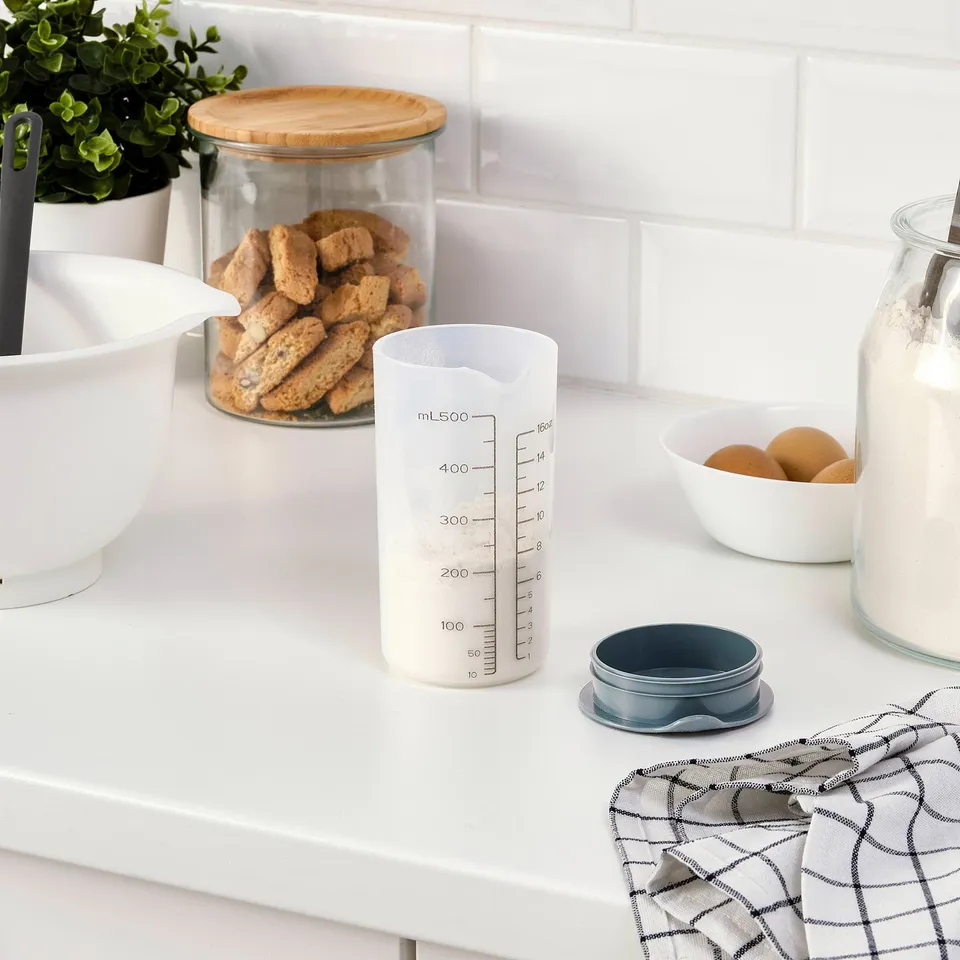 Kitchen counter with a leak-proof graduated shaker among baking ingredients.