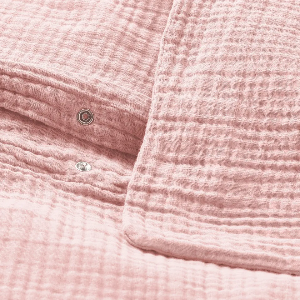 A light pink muslin duvet cover set made of breathable, organic cotton with metal press-stud closure at the bottom.