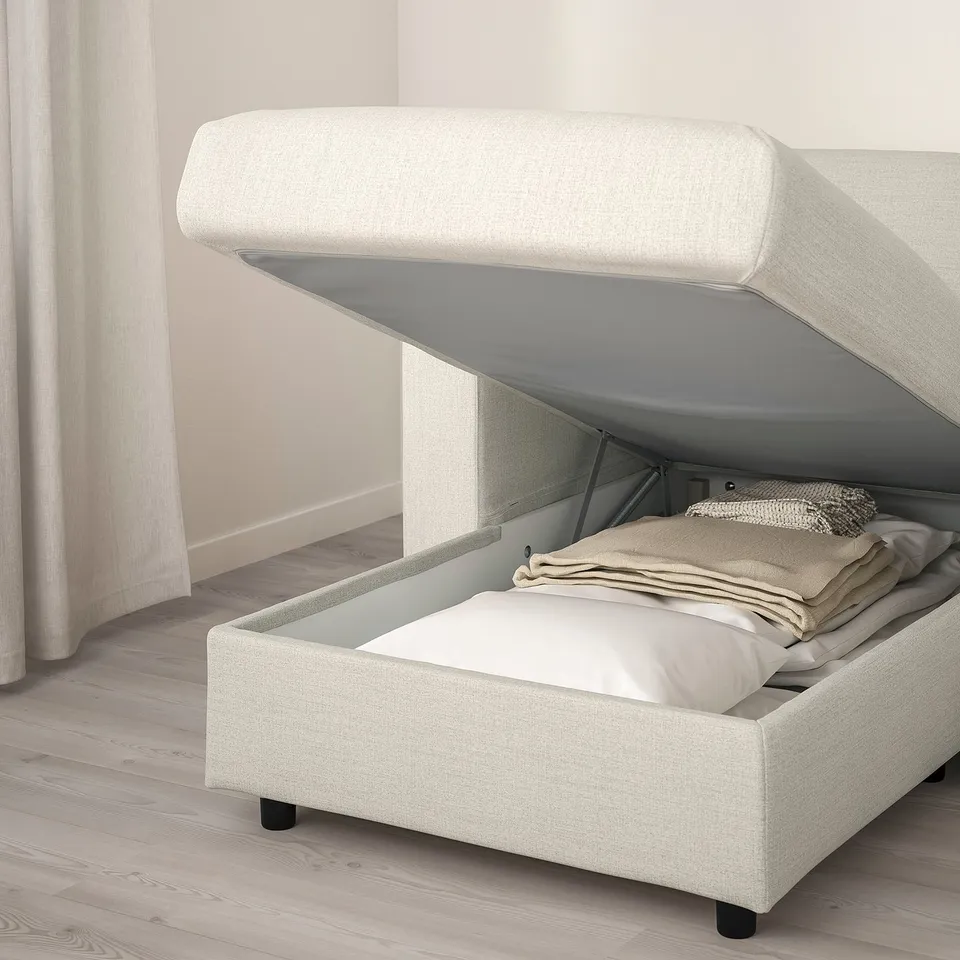 Bed with storage opened, showing folded sheets inside.