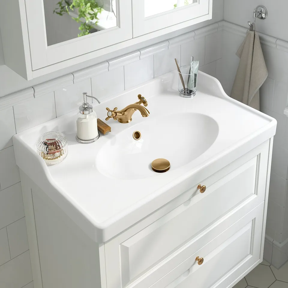 Bathroom sink with brass tap, separate hot/cold handles, soap dispenser, toothbrush holder.