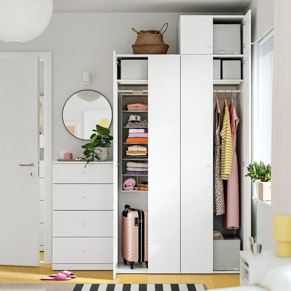 Open wardrobe showing shelves with folded clothes and hanging garments, with storage cubes and a suitcase.