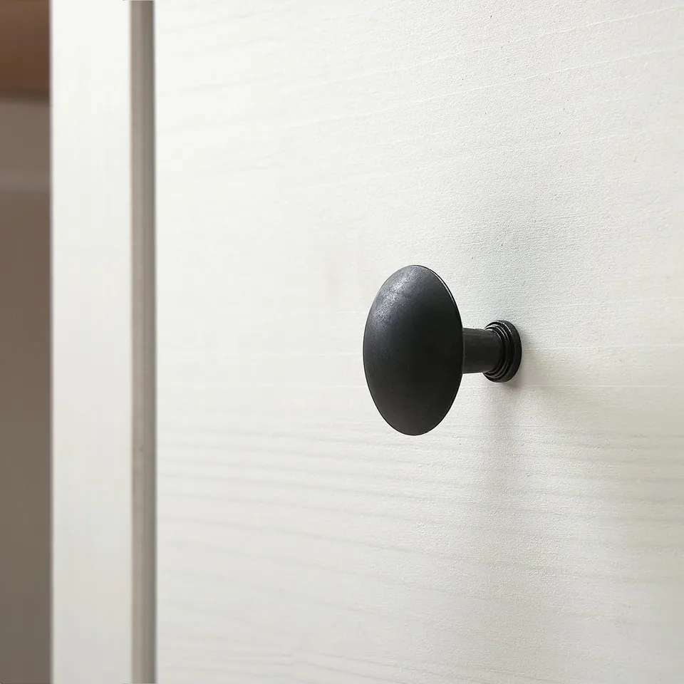 Black round doorknob on smooth white door. Sleek design, quality finish.