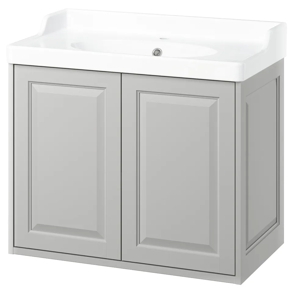A light grey TÄNNFORSEN bathroom cabinet with a ceramic sink. It double doors and a sleek, modern design.
