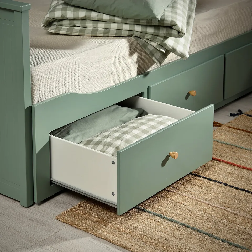 Green day-bed with open drawer under bed showing blanket.