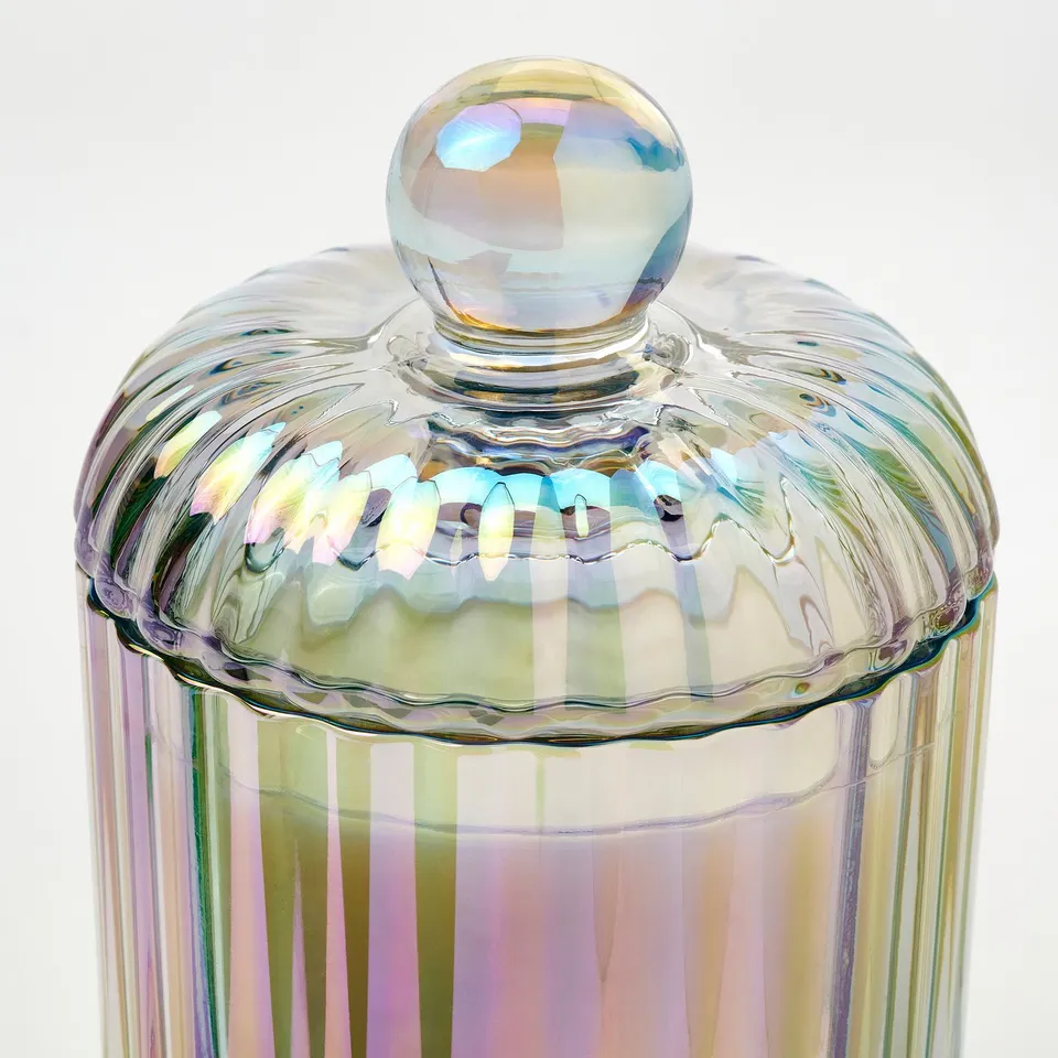 Glass jar with iridescent, wavy stripes and rounded lid, reflecting light to show quality and craftsmanship.
