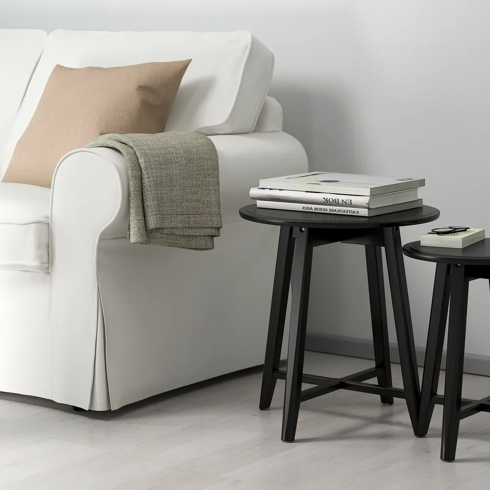 KRAGSTA nest tables: sleek black, round, modern design. Perfectly sized for compact spaces, holding books neatly beside a white couch.