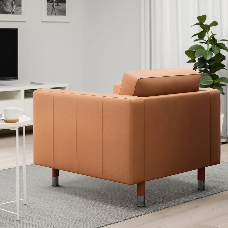 An orange upholstered armchair with wooden legs sits on a grey rug in a well-lit room.