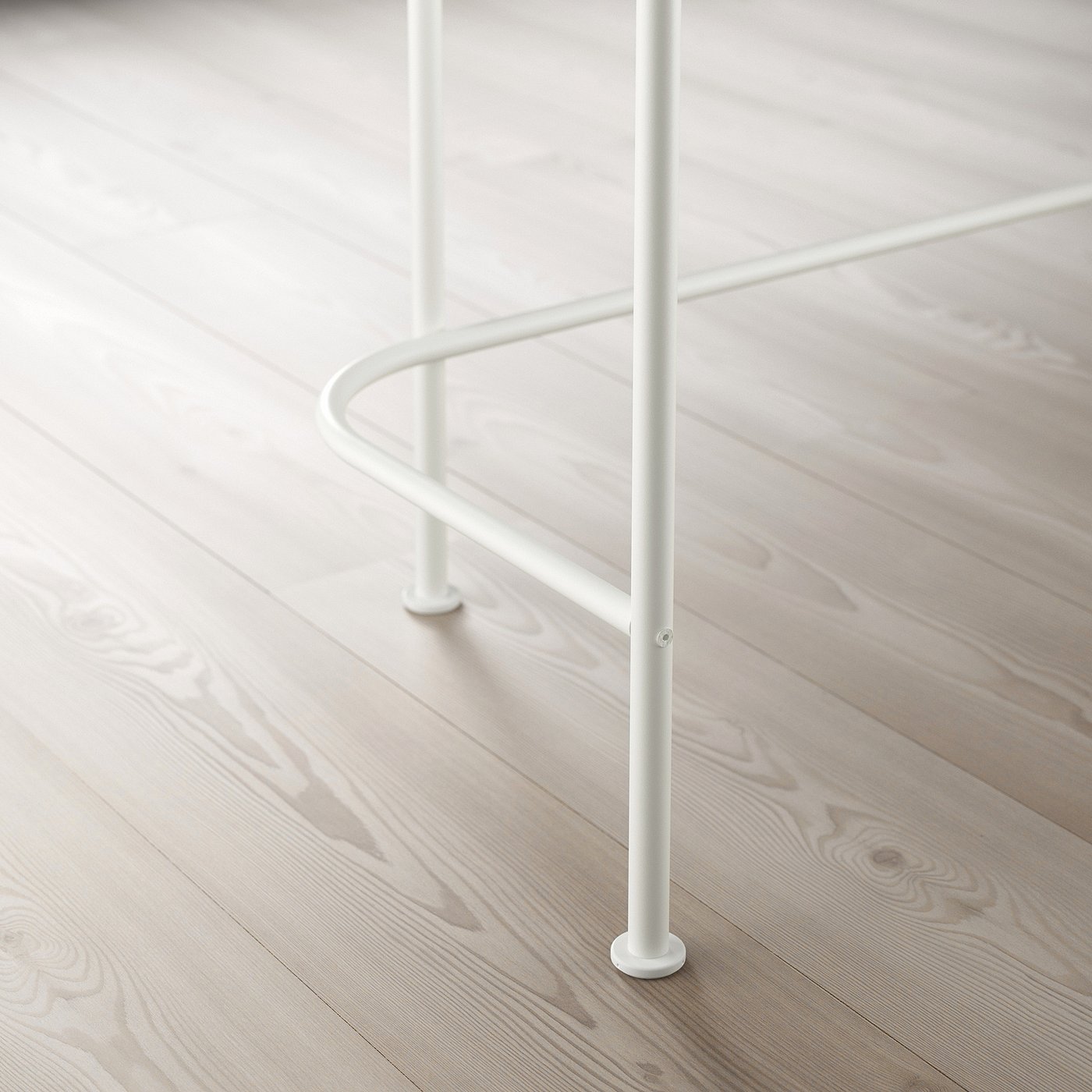 Metal table leg with adjustable feet on a wooden floor.