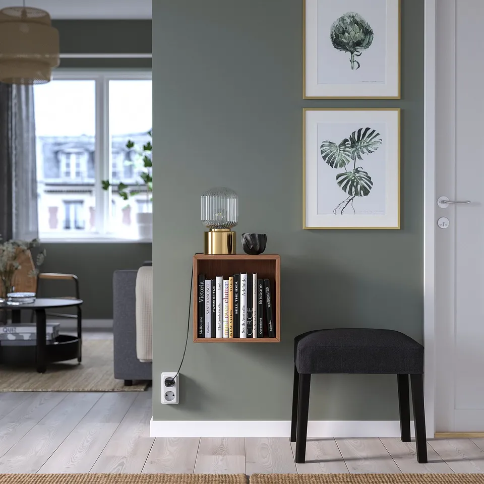 Modern living room with EKET shelf, books, decor, and green plant art.
