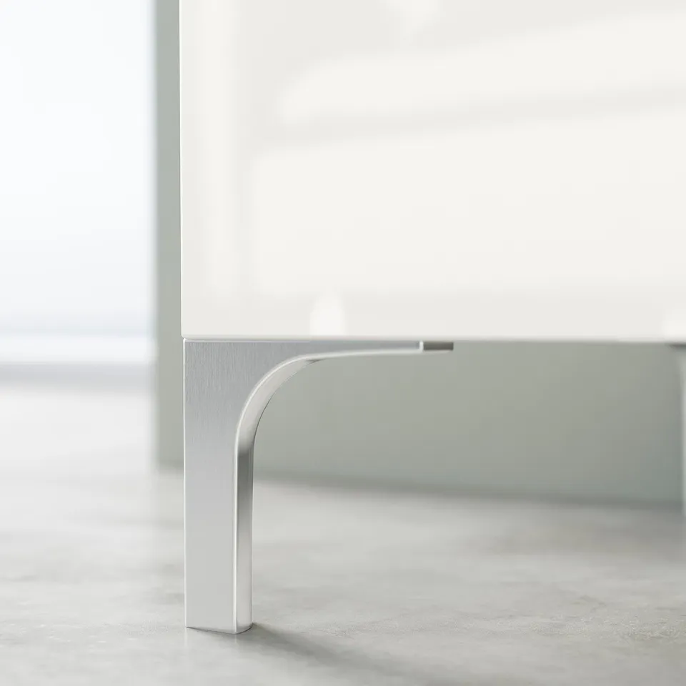 White BESTÅ tv stand with silver metal legs, showing minimalist design and cable management feature.