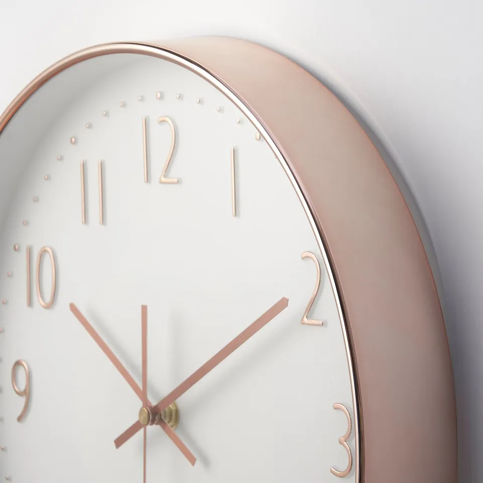 Modern rose gold wall clock with white face, thin hands, and numbers. High-quality design, precise and silent.