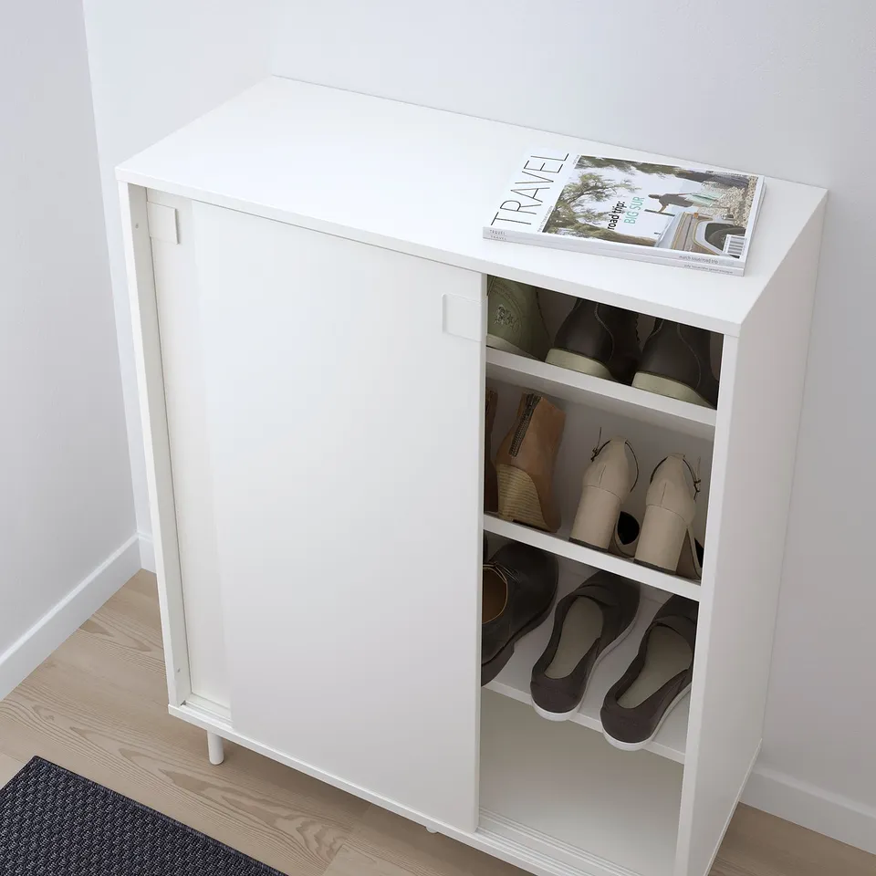 White shoe cabinet holds 24 pairs, with angled shelves for organised storage. Sliding doors save space, ideal for small areas.