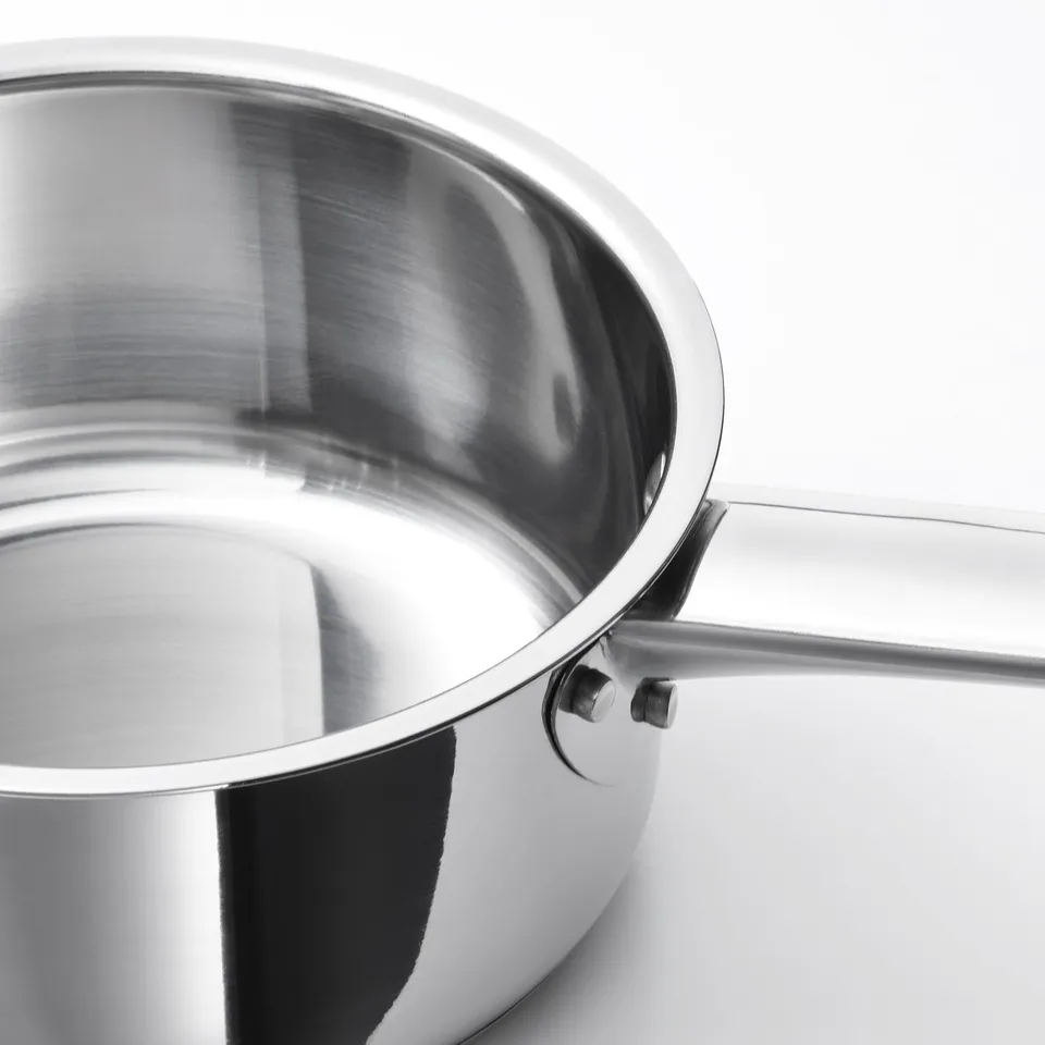 Stainless steel saucepan with thick base, suited for induction hobs and ovens. Shiny, sleek finish, reflecting light.