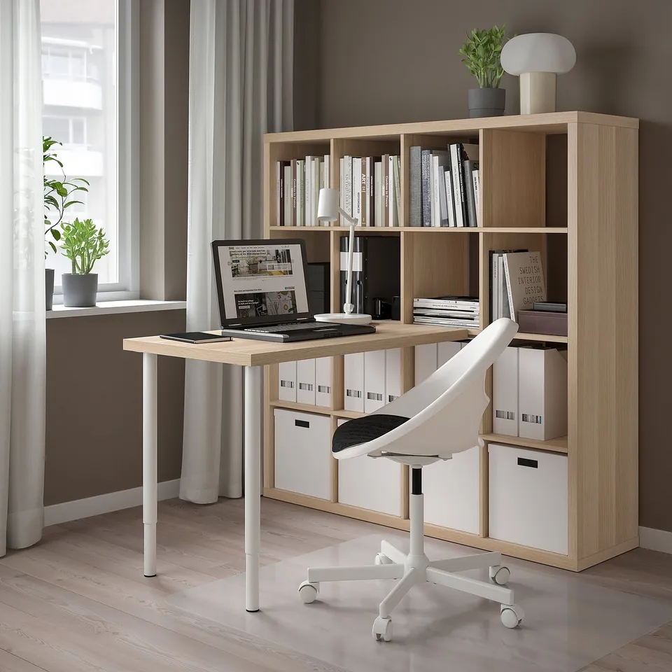 Modern home office with KALLAX shelves, laptop, and plants.