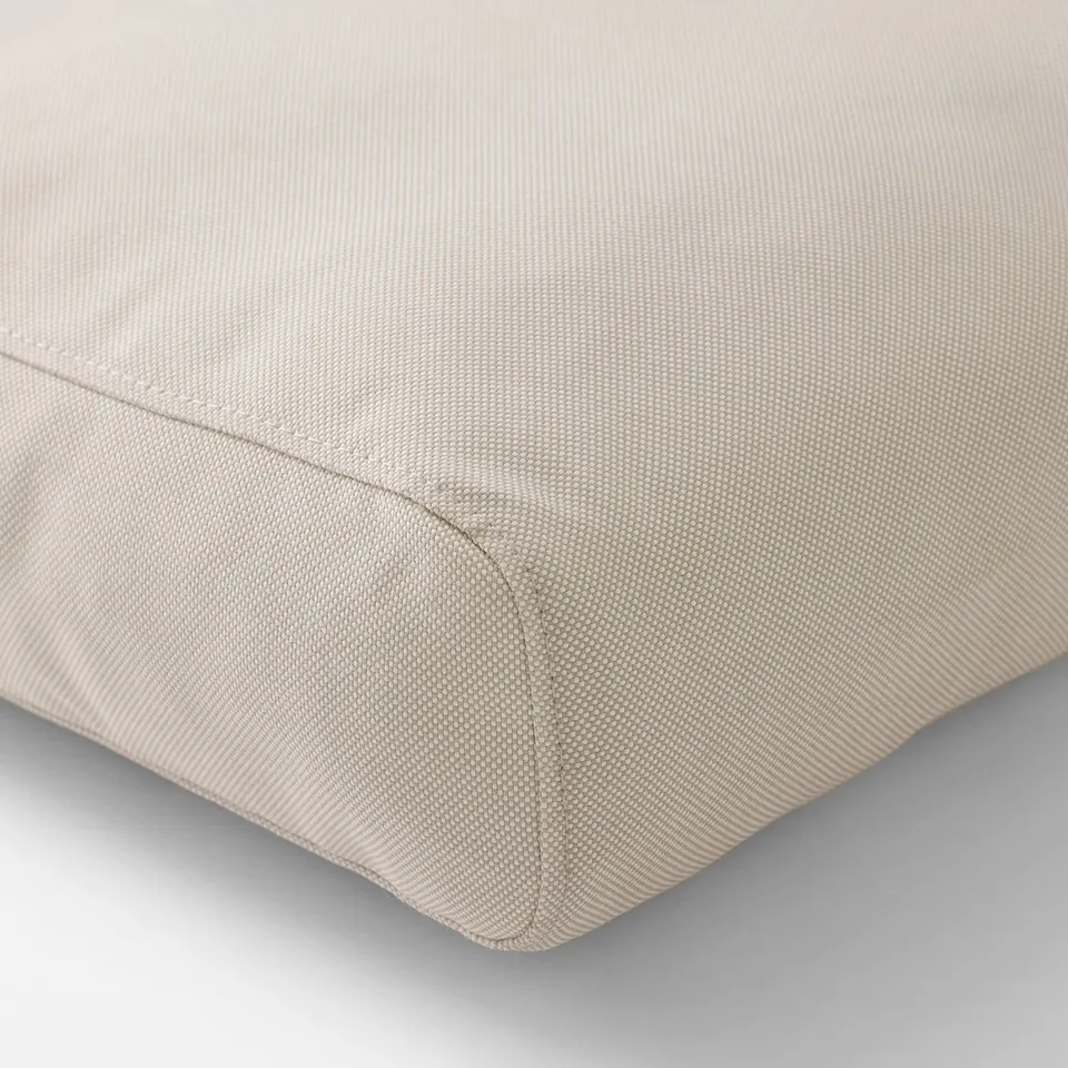 High-quality, light beige outdoor cushion with even stitching and textured fabric, providing comfort and durability.