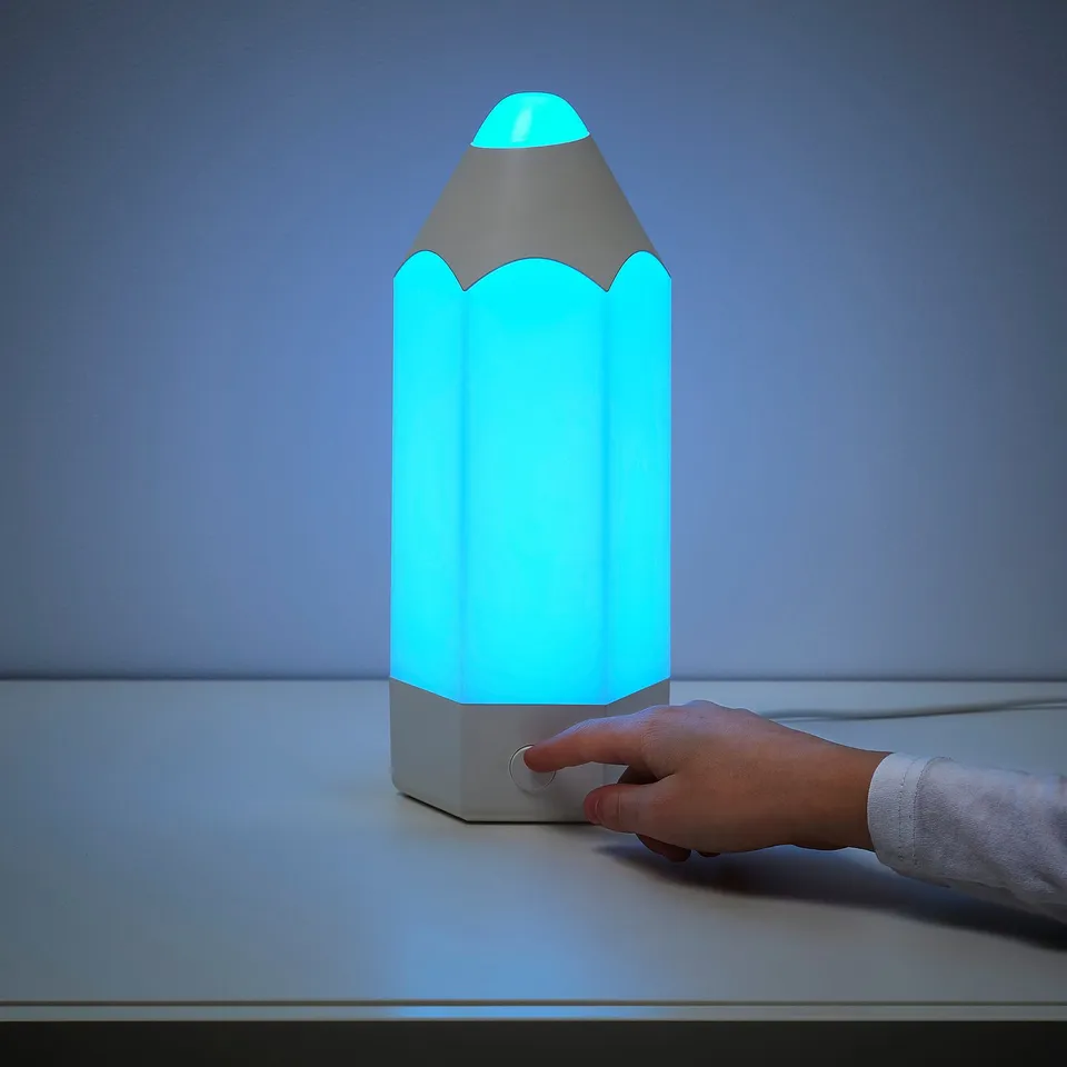 Childs hand pressing button on large, illuminated pencil-shaped nightlight.