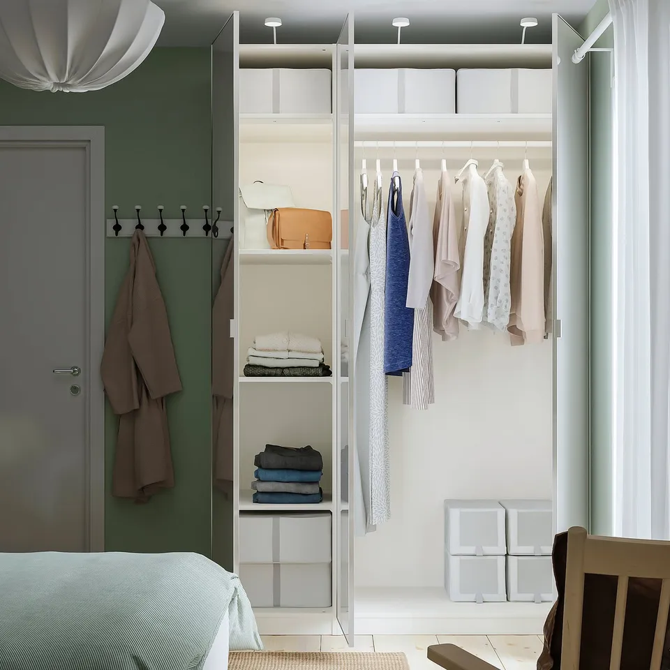 A modern closet stores clothes on hangers and shelves, with a hanging rod and integrated lighting.
