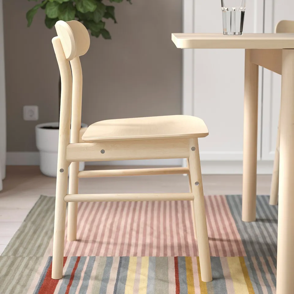 Wooden chair with rounded seat & back, near table. Warm, natural grains. Sturdy for home use.