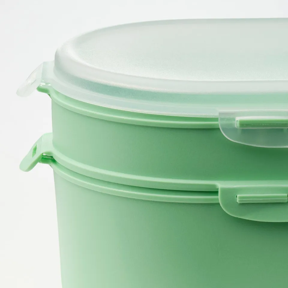 Two green plastic food containers stacked, sealed with clear lids. Quality design, secure latches.
