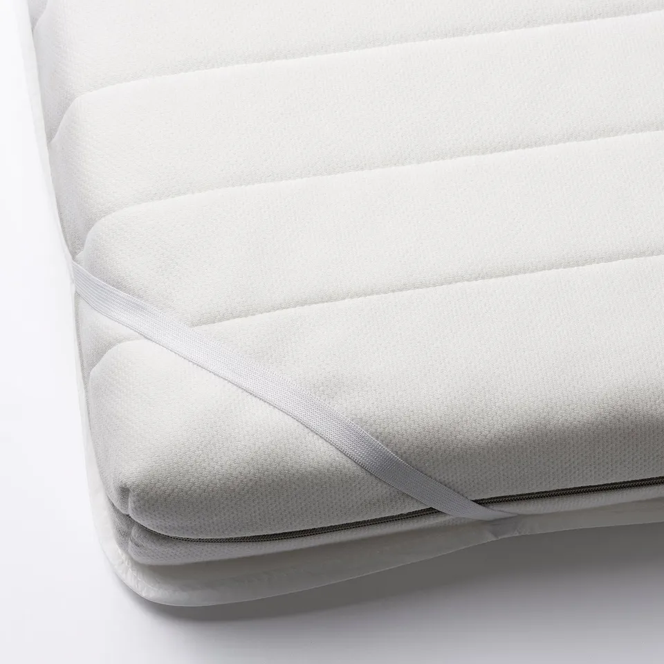 White mattress protector with elastic corners, shown partially folded, designed to guard against spills and keep the mattress clean and dry.