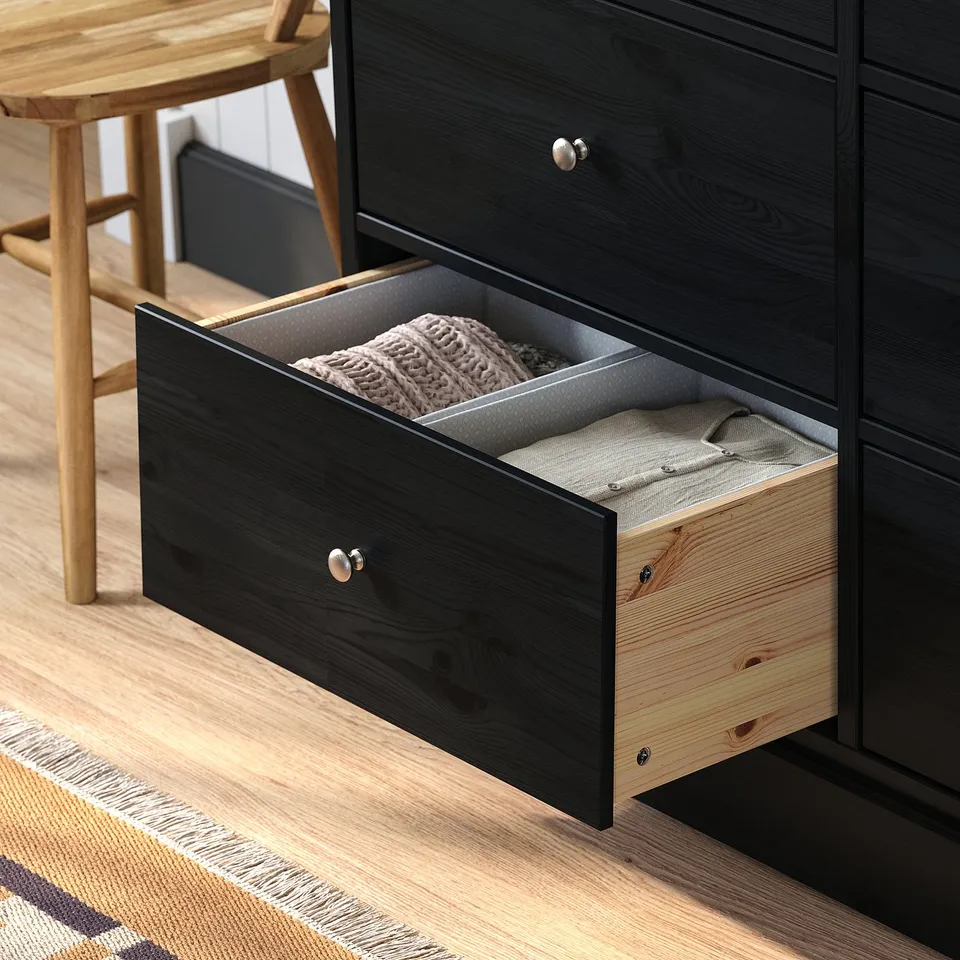 Black dresser drawer open, showing folded clothes inside. Drawer has metal knobs and is part of HAVSTA series.