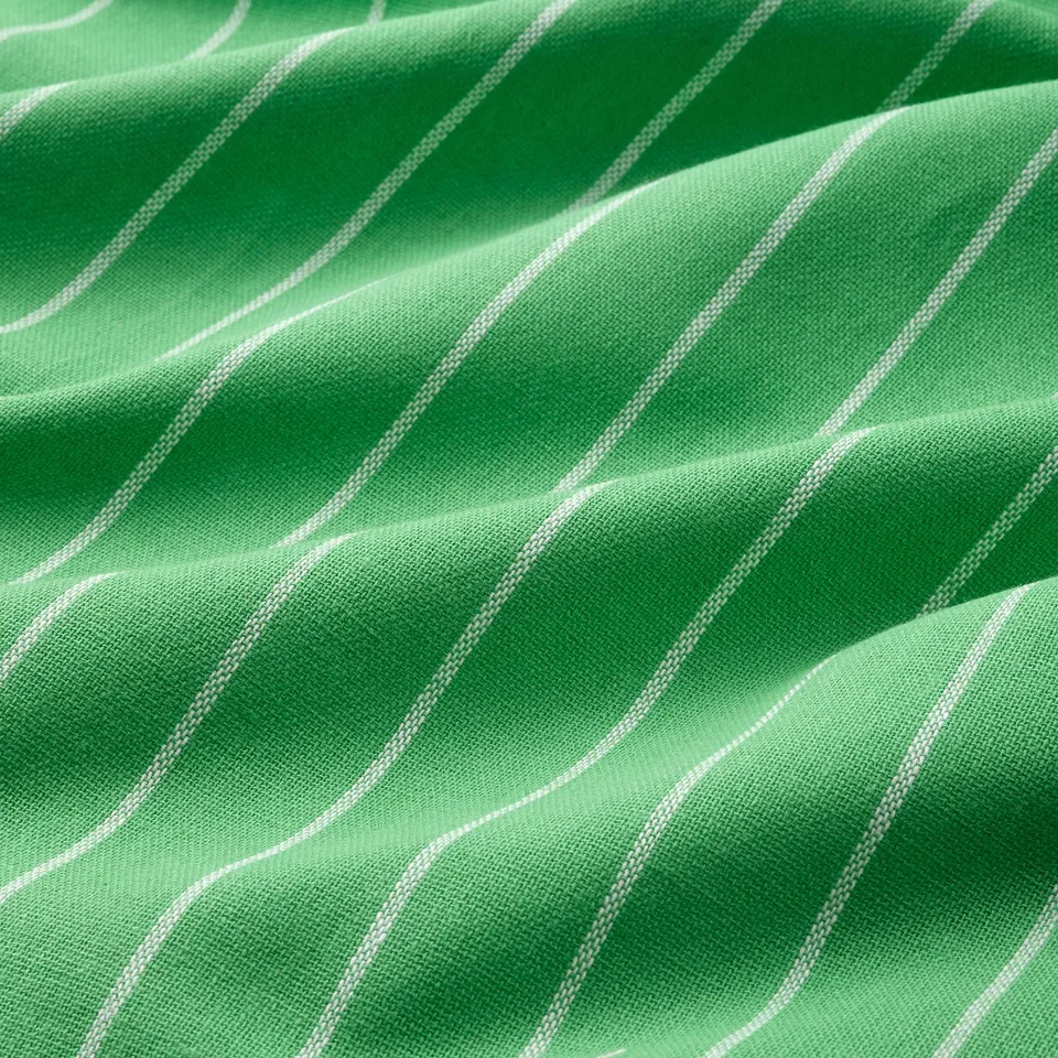 Close-up on bright green striped kitchen towel, showcasing its smooth, woven texture and neat, even stitching.