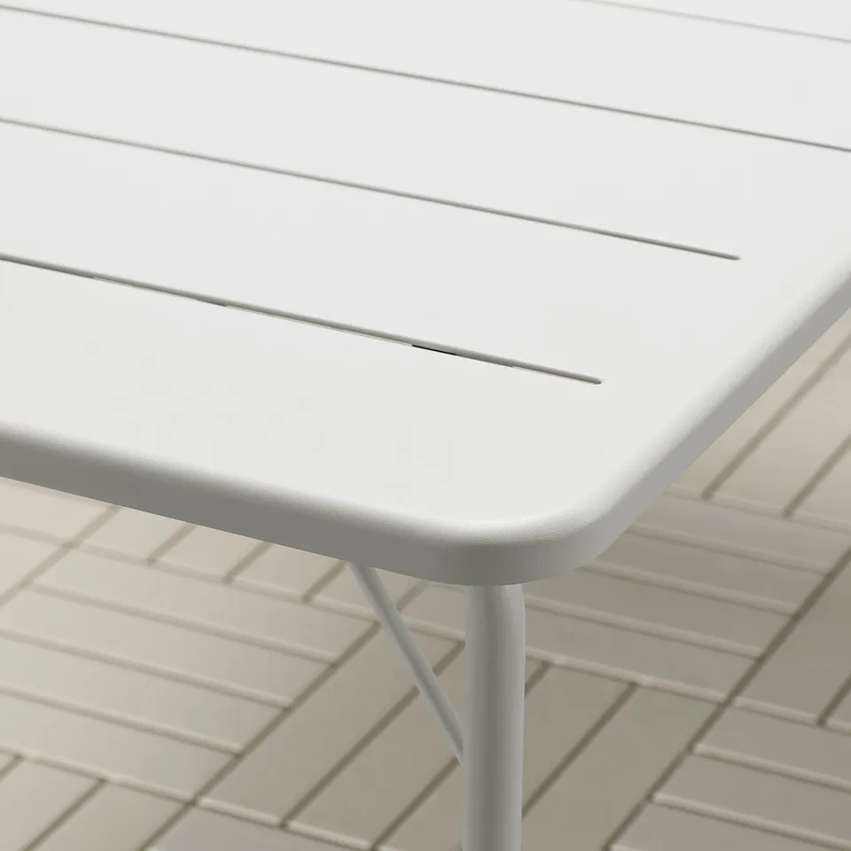 Close-up of modern outdoor table with sleek, folded design and smooth edges, showcasing durable and weather-resistant white surface.