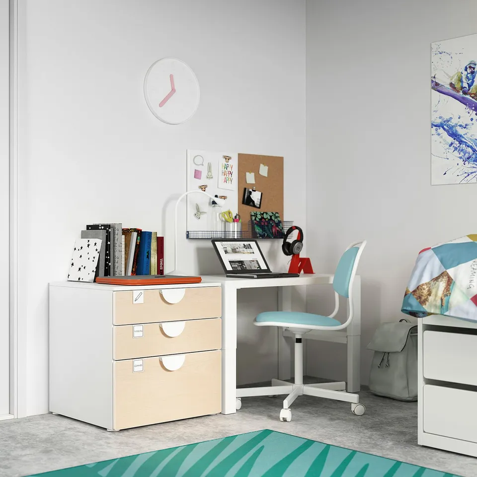 Childs study area with white desk, blue chair, and colourful decor. Includes books, laptop, and clock.