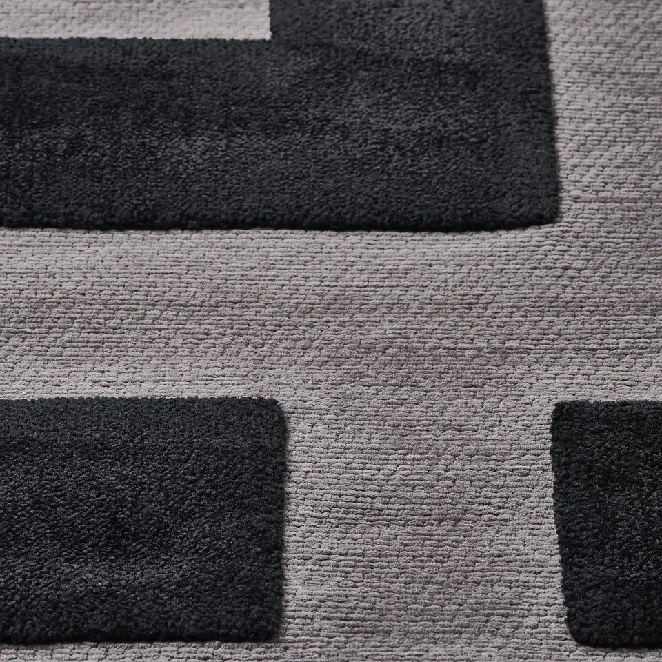 Modern geometric rug detail, featuring black and light grey squares. Soft, raised pattern for tactile appeal.