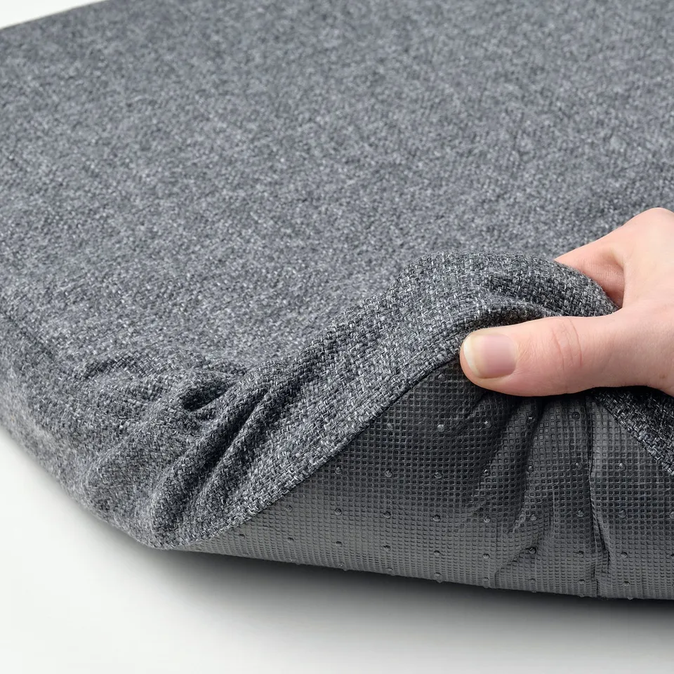 Hand holding grey fabric, showcasing soft, non-slip backing on a memory foam chair pad.