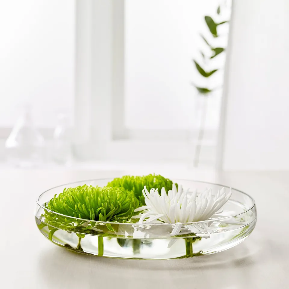 Clear glass bowl displays green and white flowers, arranged for decoration.