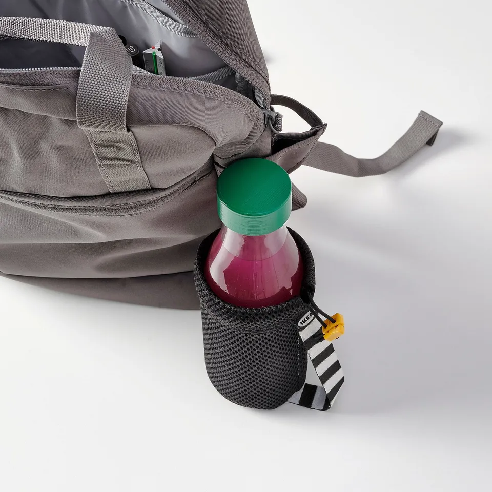 Grey backpack with side mesh pocket holding water bottle with green cap, labelled SPARTANSK.