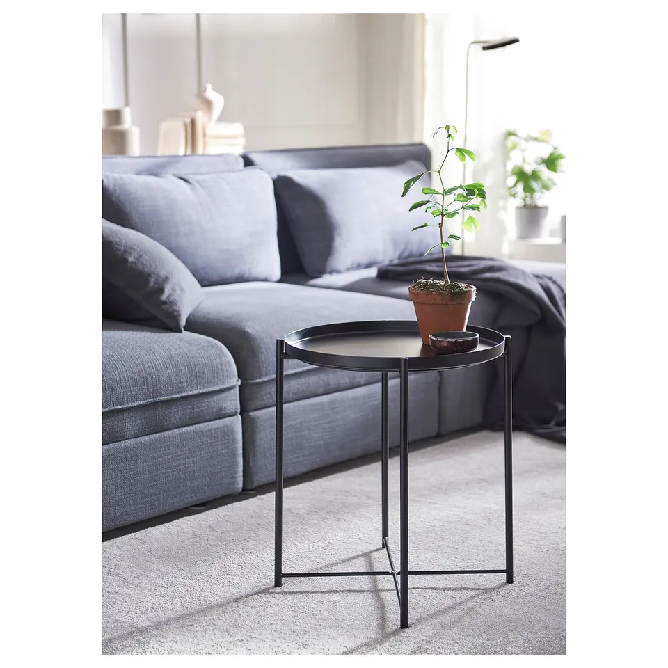 Modern living room with a grey sofa and a small black GLADOM side table holding a potted plant and a small tray.