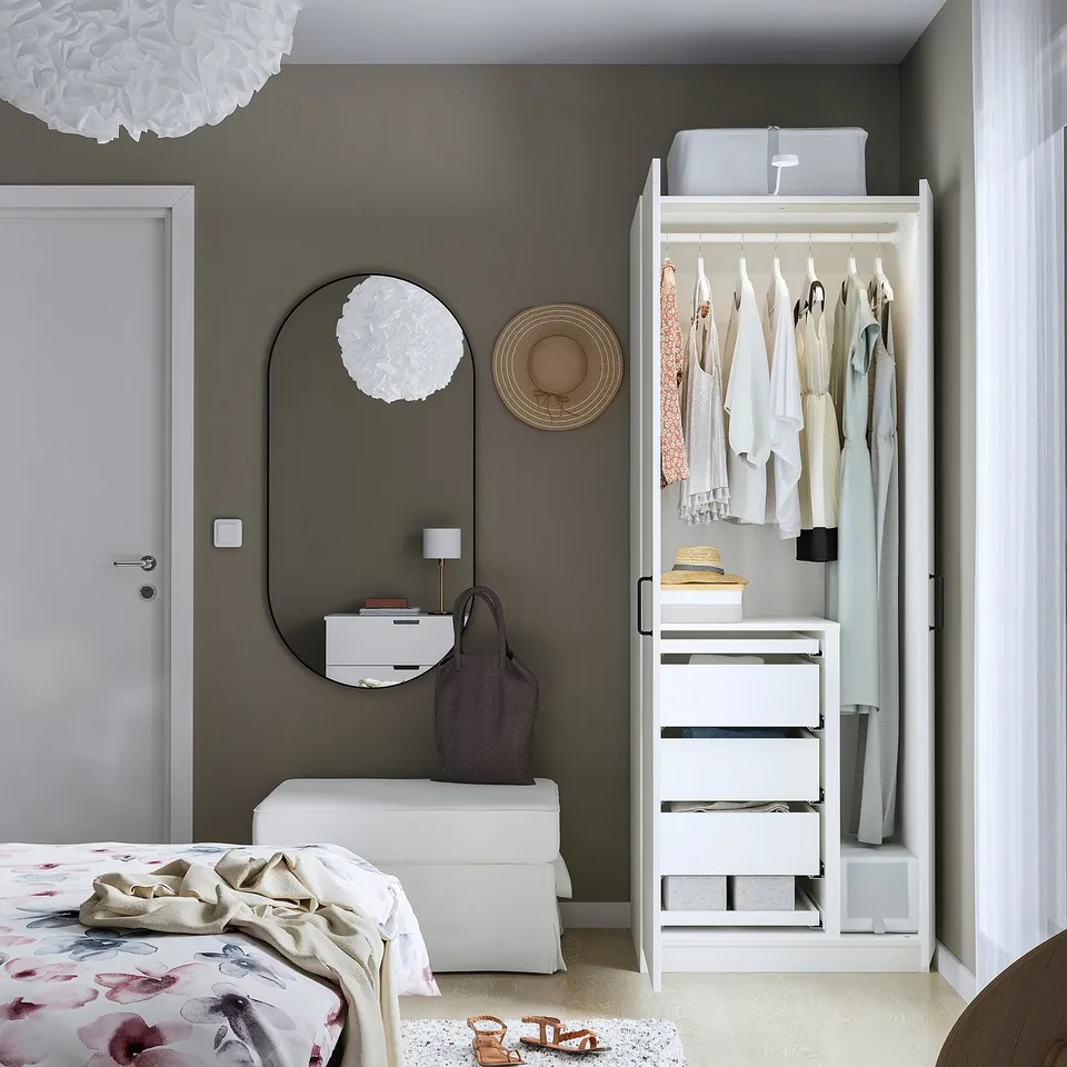 Modern bedroom with open PAX wardrobe, showing hangers and drawers. Grey walls and floral bedding.