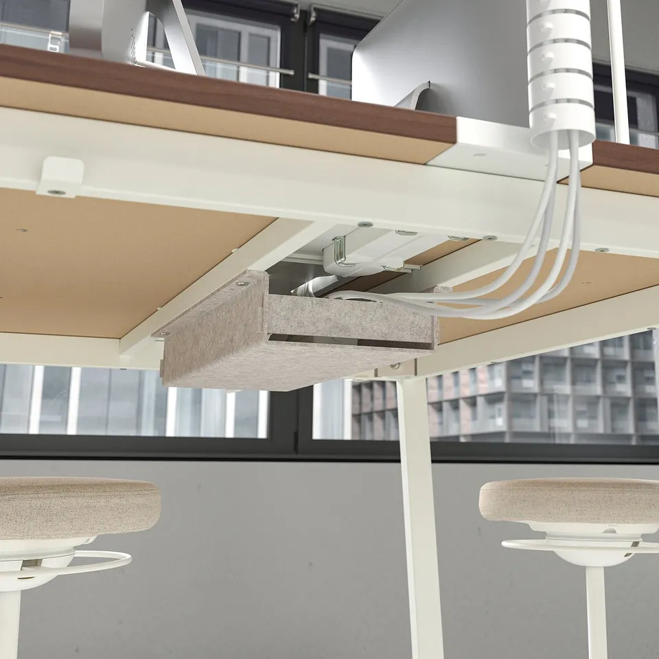 Under desk cable management with white cord at office workstation, showing organised setup with footrest.