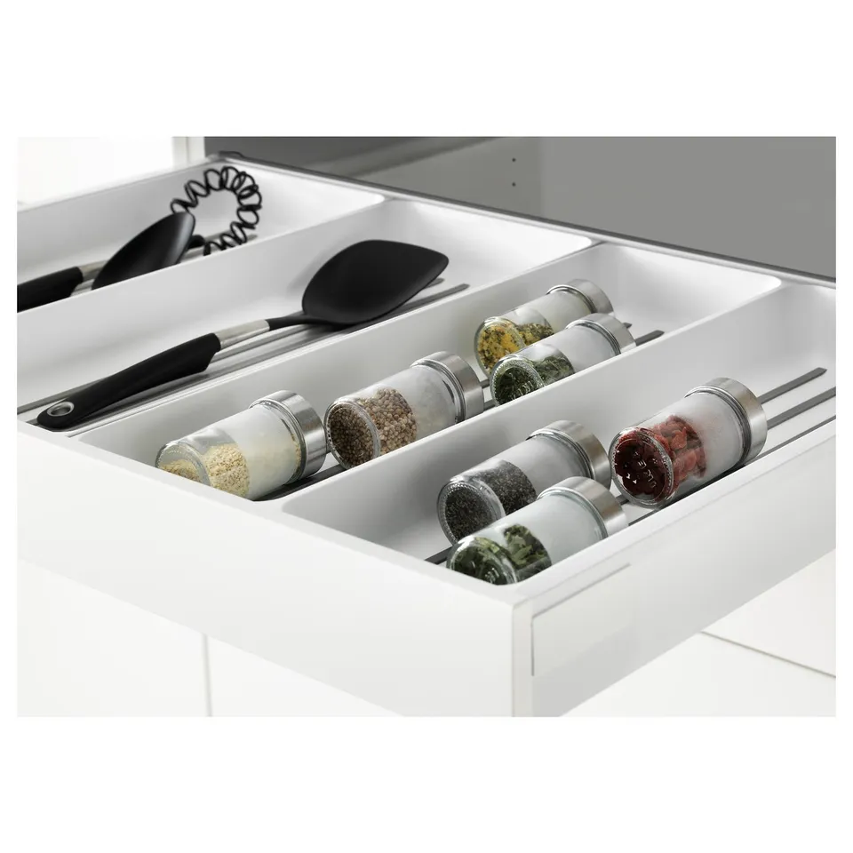 Open kitchen drawer with spice jars and utensils, showcasing organised storage.