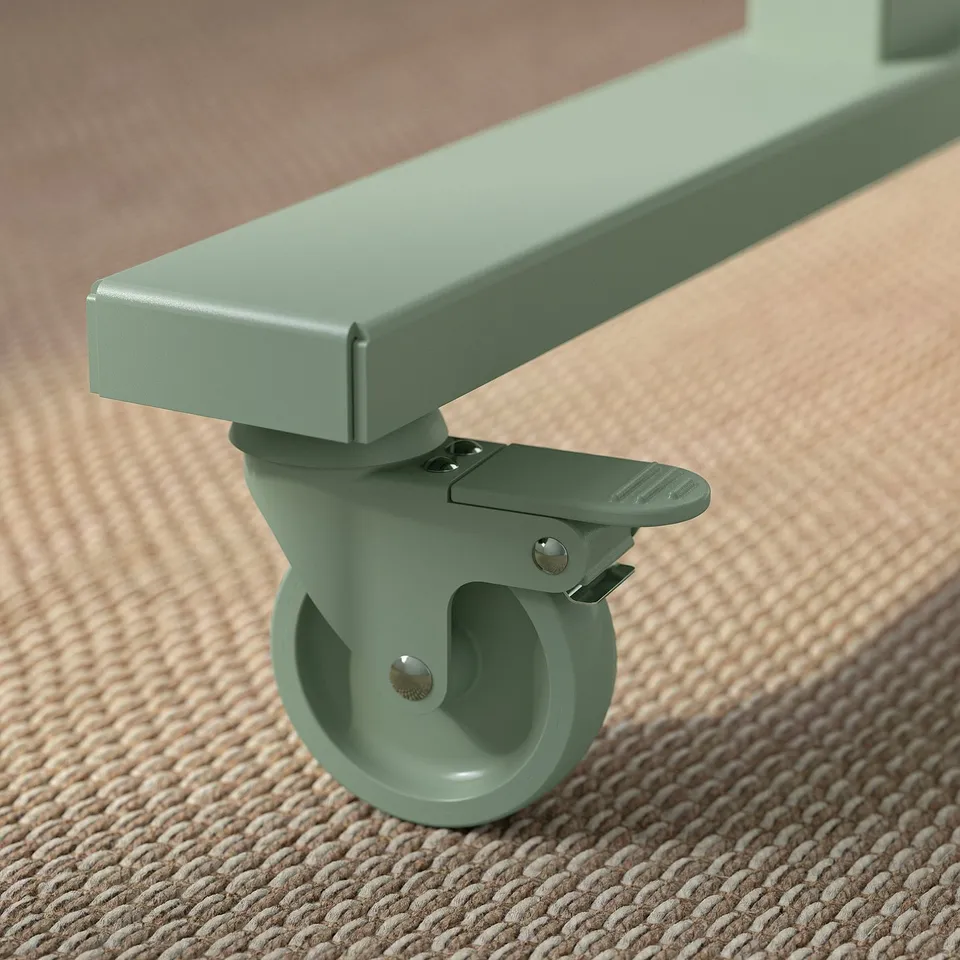Close-up of a green foldable tables castor with brake mechanism on a textured rug.