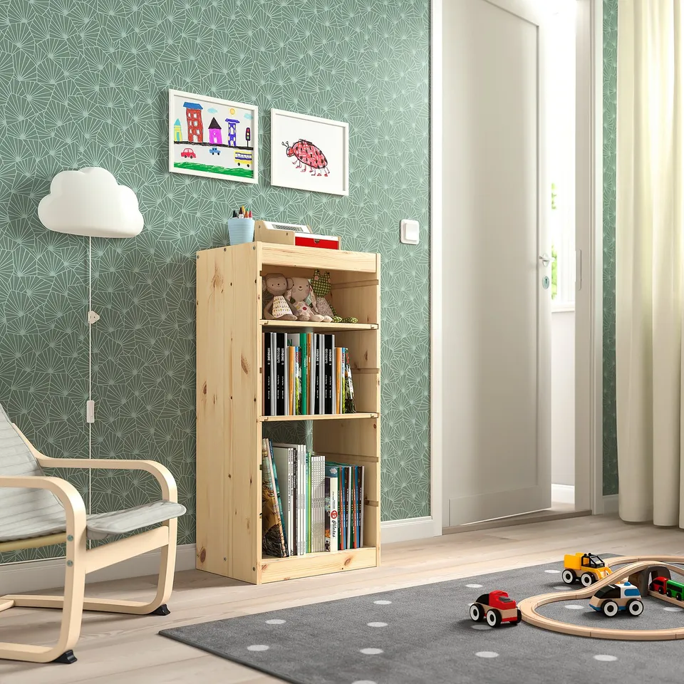 Childrens room with TROFAST light wood storage unit filled with books and toys. Colourful wall art and a grey rug with toy cars.