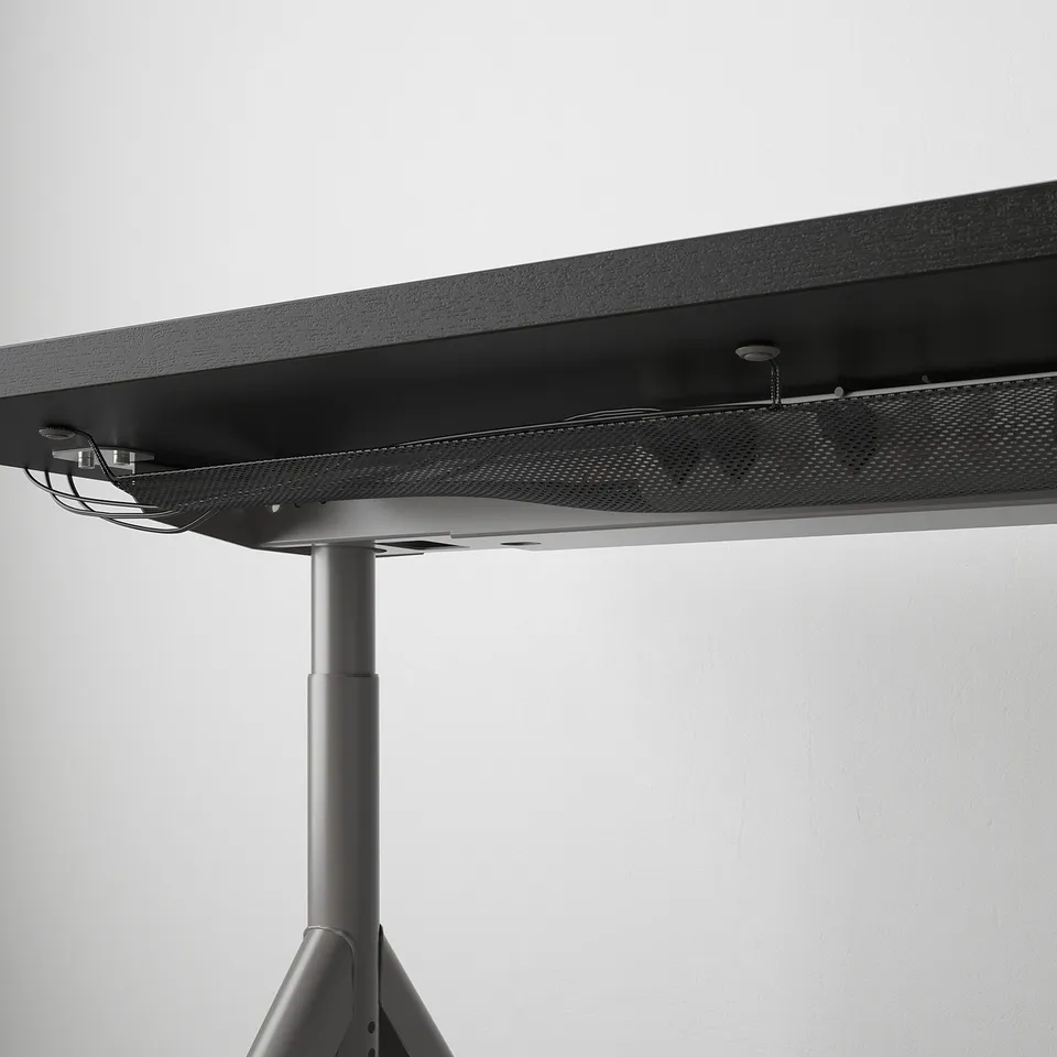 Black desk with adjustable legs and cable management net beneath the tabletop.