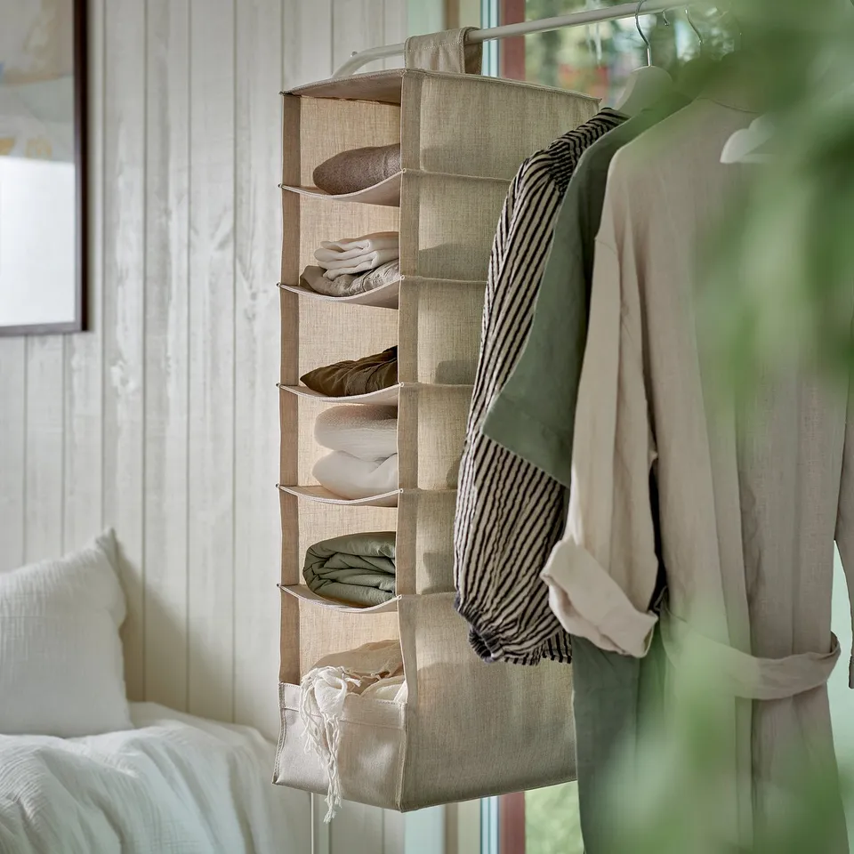Hanging storage with multiple compartments for organising folded clothes, ideal for wardrobes and small spaces.