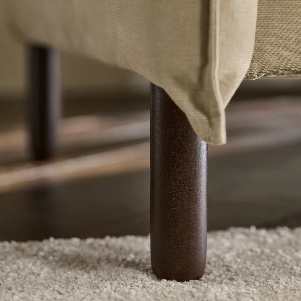 Close-up of sofa leg, showing smooth, dark finish and sturdy construction.