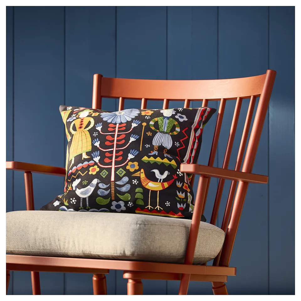 Vibrant cushion on an orange chair, dark blue wall.