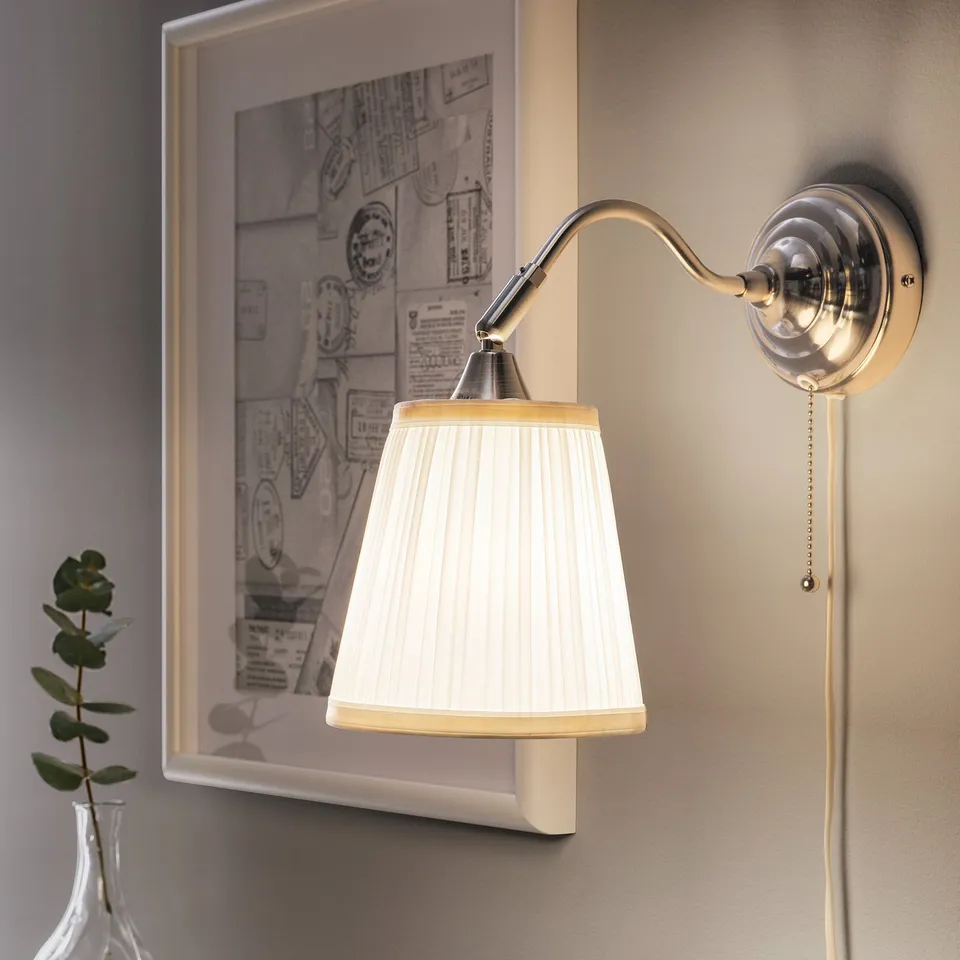 Wall-mounted lamp with adjustable shade, lit by a pull switch.