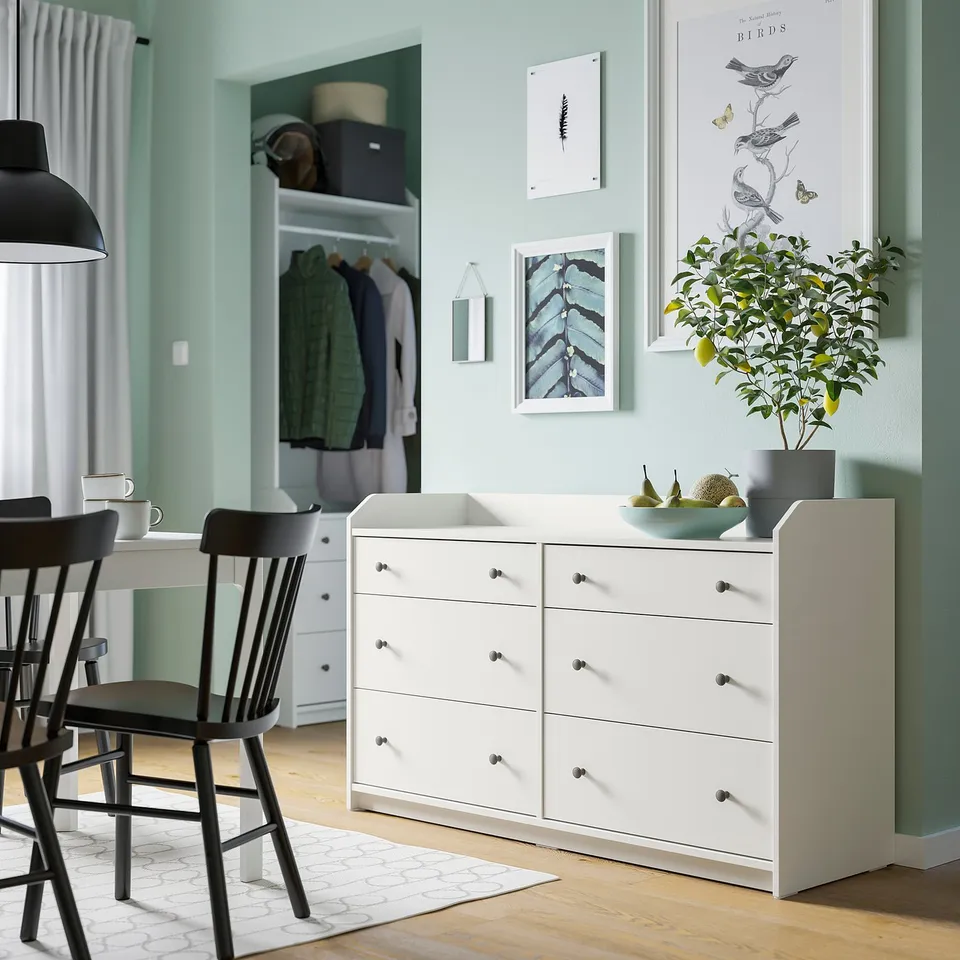 Modern bedroom with HAUGA chest, plant, art, black chairs.