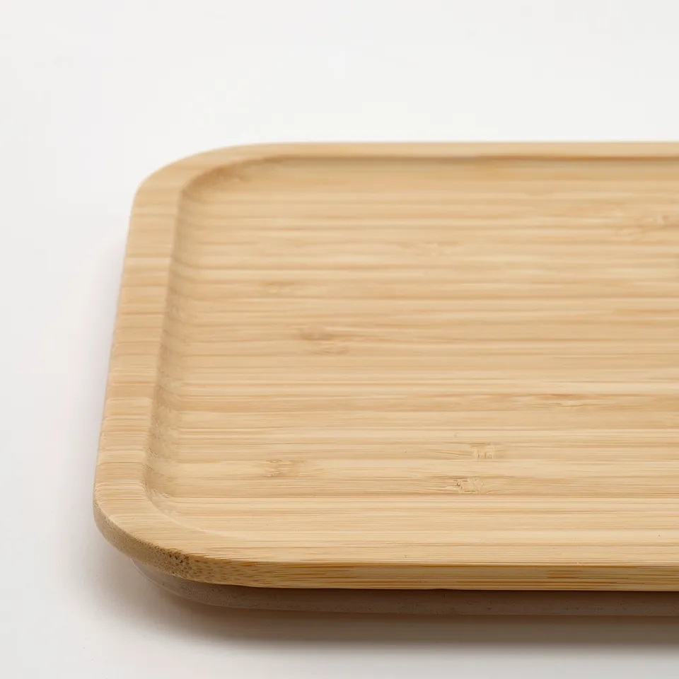 Flat, rectangular bamboo lid, smooth surface, rounded edges, sleek finish, suitable for food storage or coaster.
